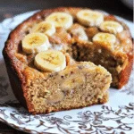 Part de gâteau moelleux à la banane, sans farine, sans sucre ajouté ni lait, servie sur une assiette en céramique avec une cuillère en bois.